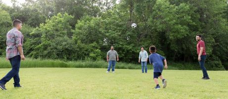 Vier Männer und ein Junge spielen Fußball
